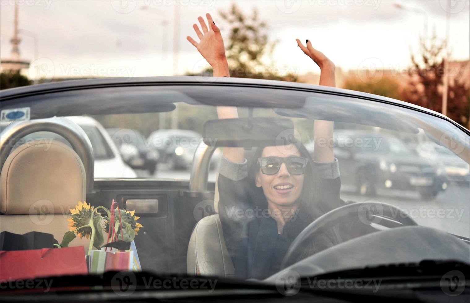 Happy beautiful woman driving a sports convertible car in the city photo