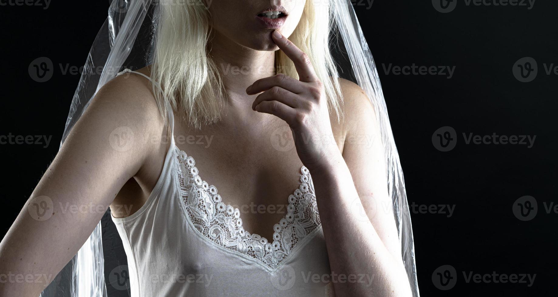 Beautiful blond woman wearing white nightgown posing on black  background. photo