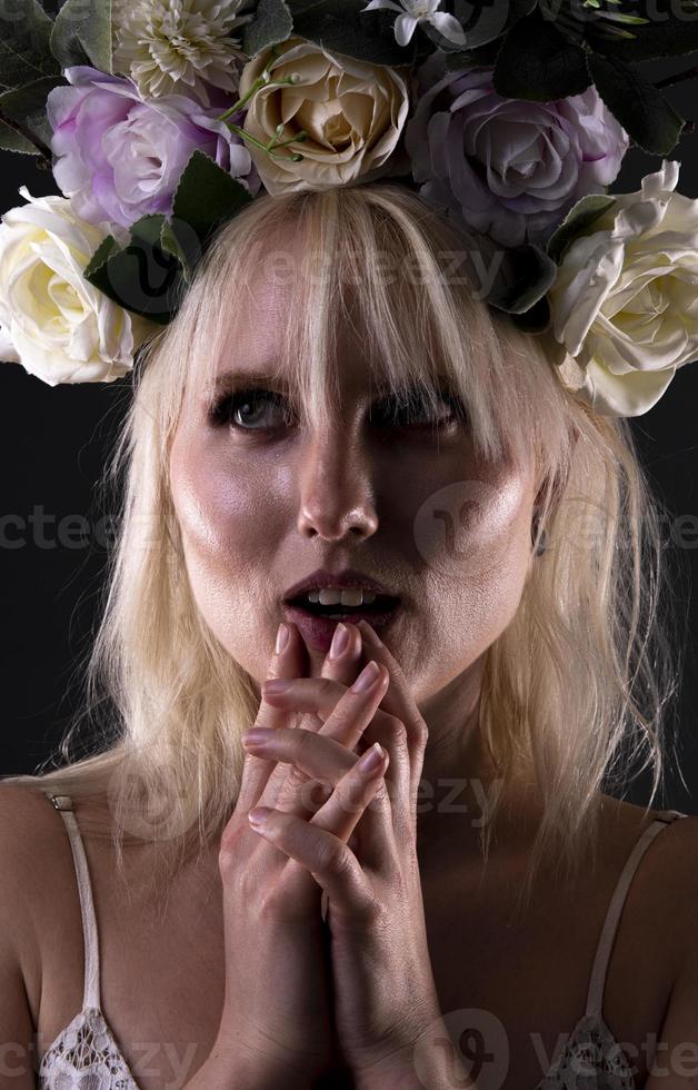 Beautiful blond woman with flowers on her head posing on black  background. photo