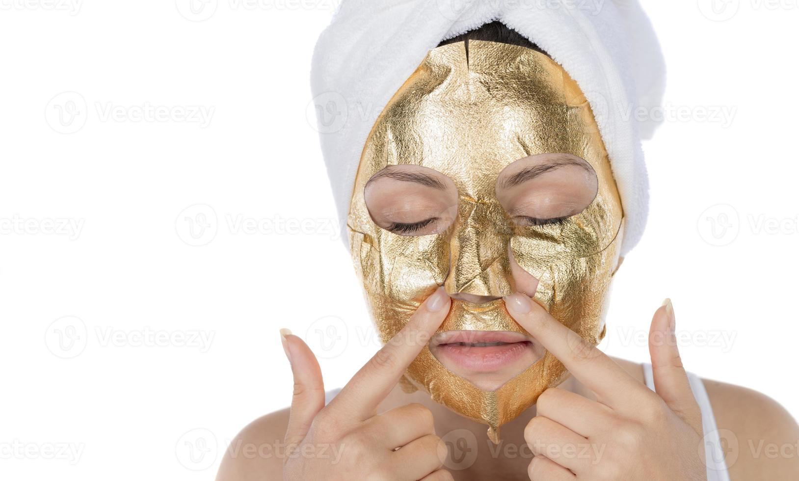 procedimiento cosmético, la cara de la mujer con máscara de oro sobre fondo blanco foto