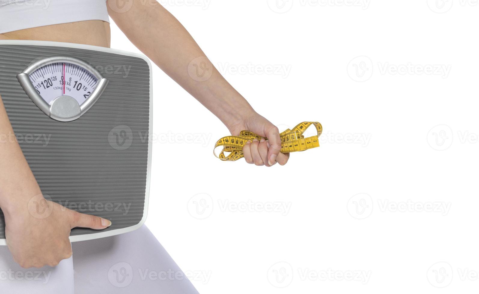 Female model holding scale and measuring tape over white background photo