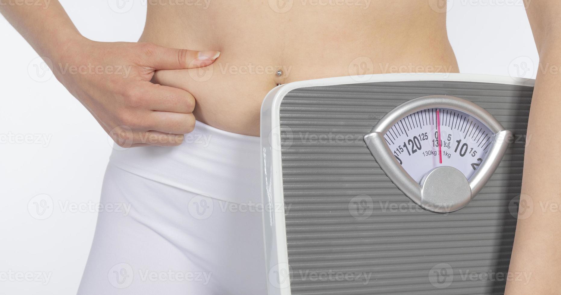 Female model holding scale and measuring tape over white background photo