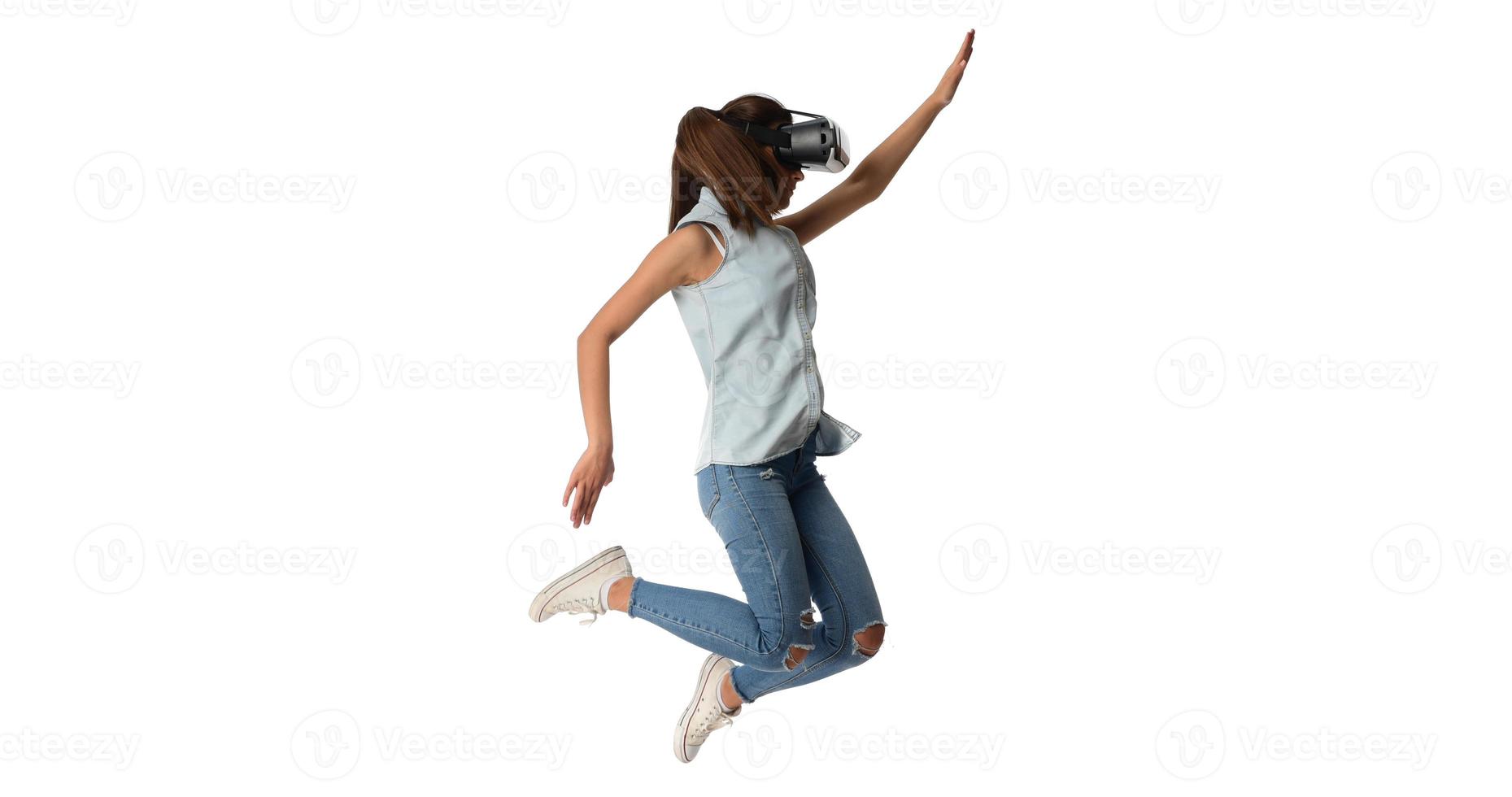 Pretty cute excited female in VR headset looking up and trying to touch objects in virtual reality photo