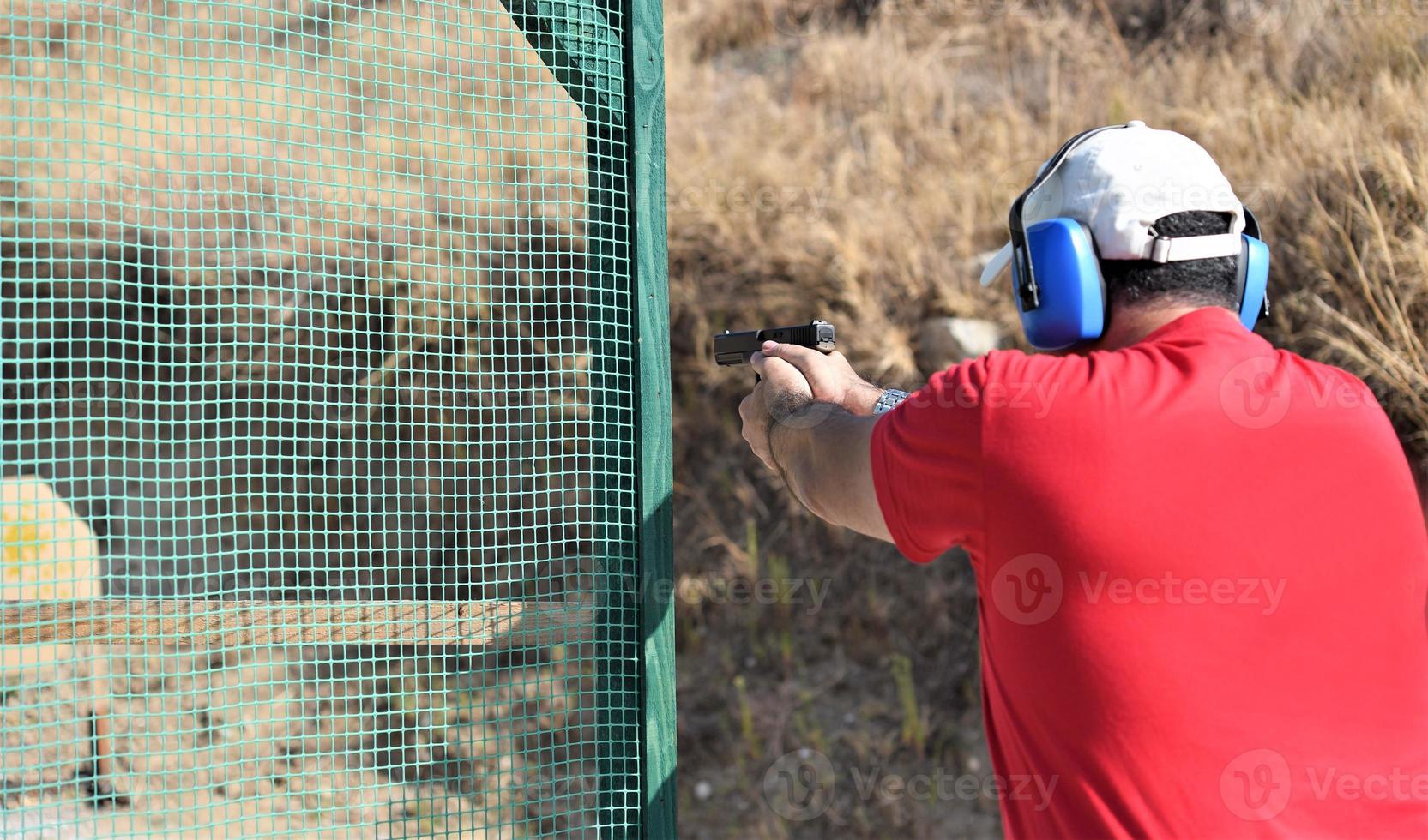 back view of a man shooting his gun on a practice ranch. photo