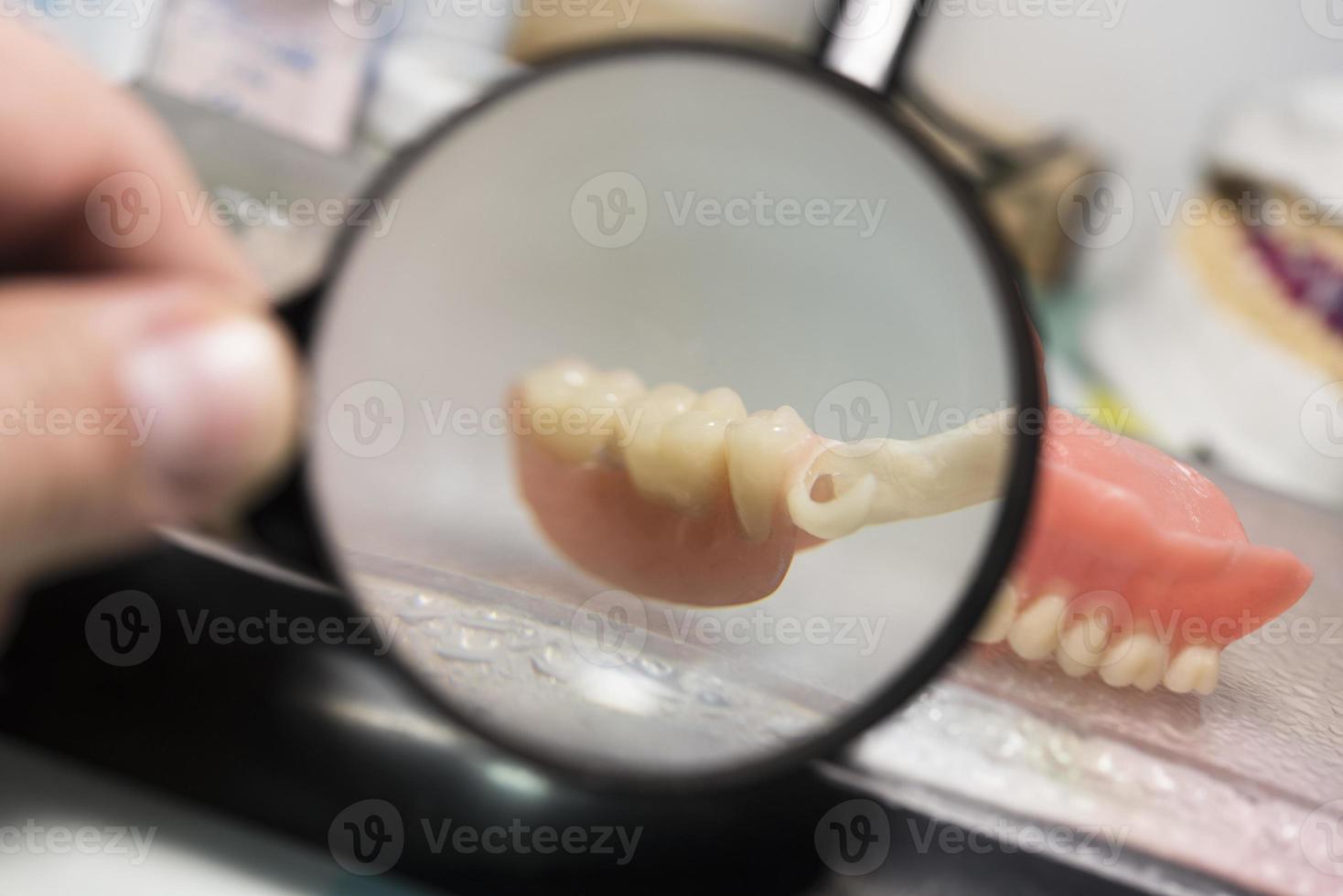 Dental prosthesis, dentures, prosthetics work. Prosthetics hands while working on the denture, false teeth, a study and a table with dental tools photo