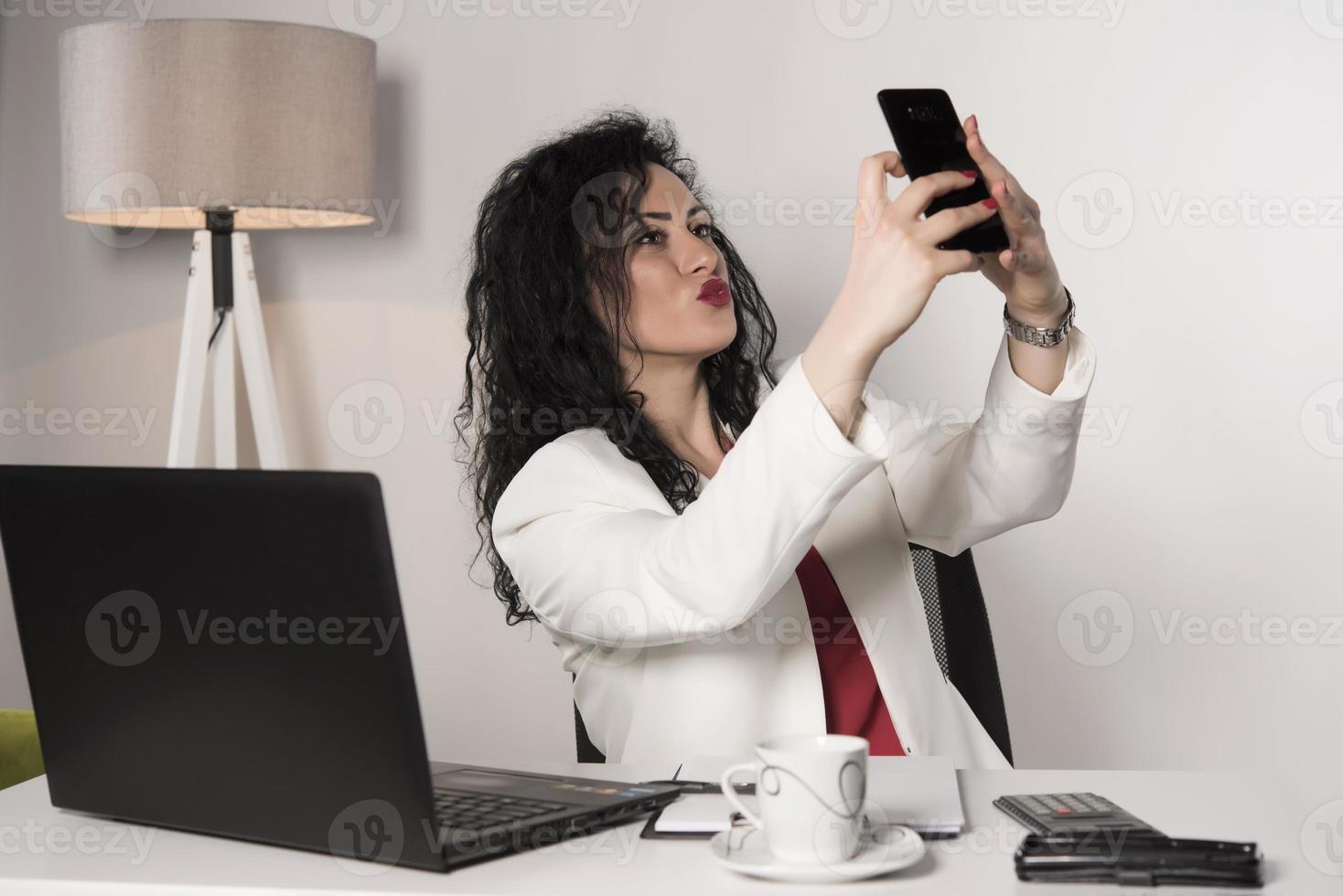 beautiful business woman sitting in her office and talking on the cellphone. business concept photo