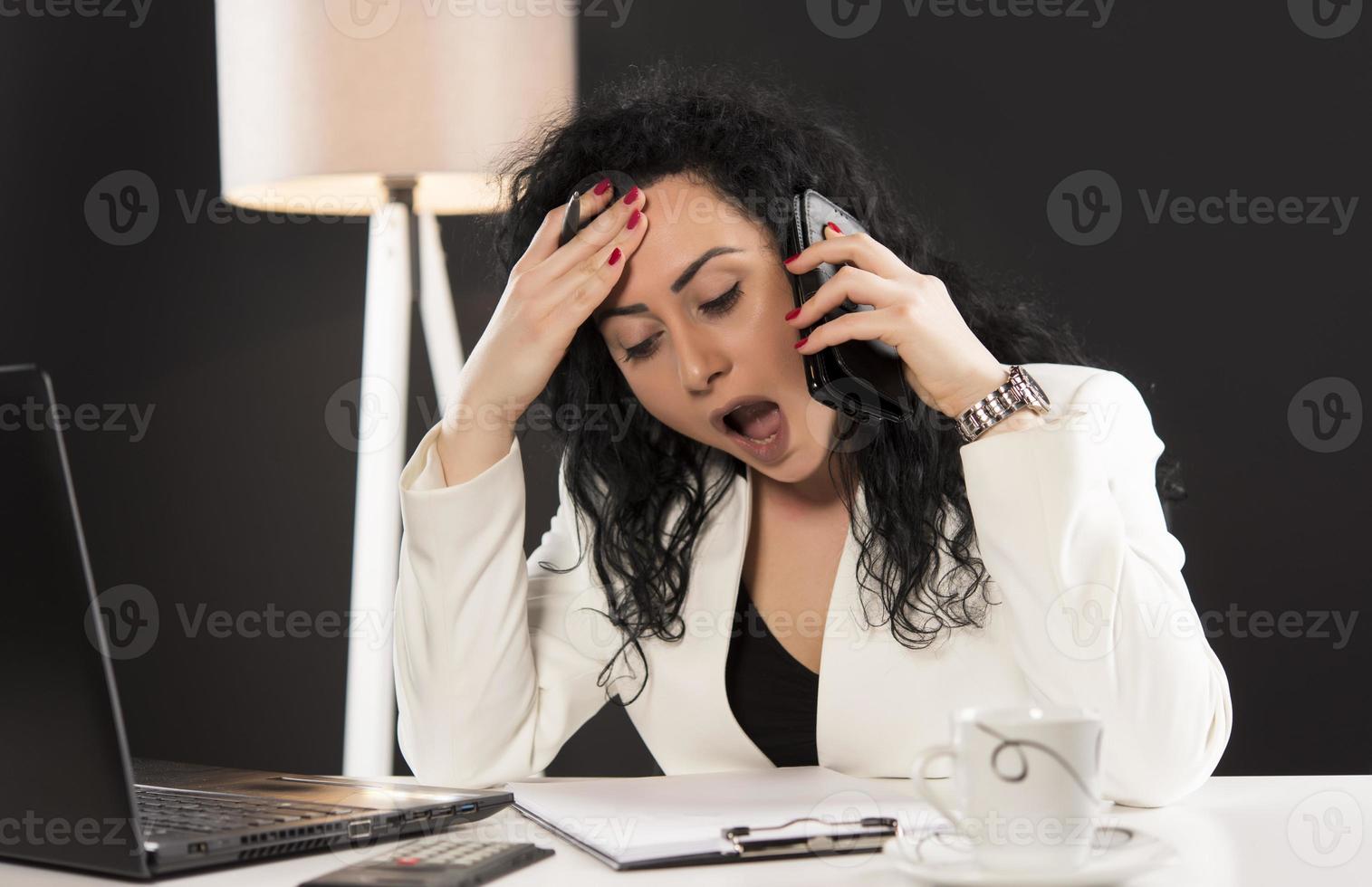 beautiful business woman sitting in her office and talking on the cellphone. business concept photo