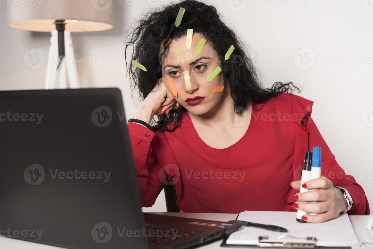 Pretty female model with a lot of post it notes working in her office. photo