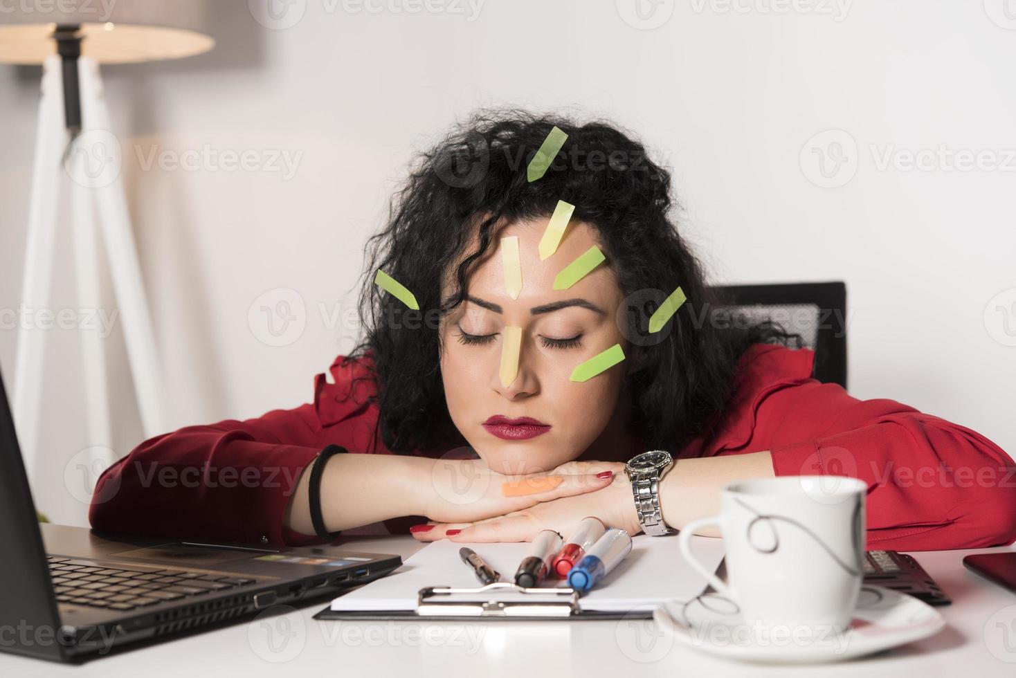Pretty female model with a lot of post it notes working in her office. photo