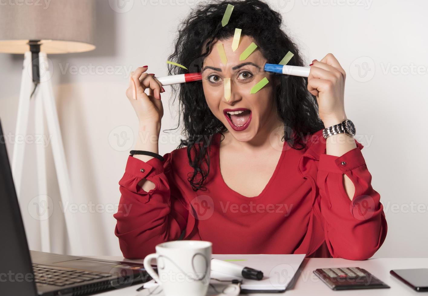 Pretty female model with a lot of post it notes working in her office. photo