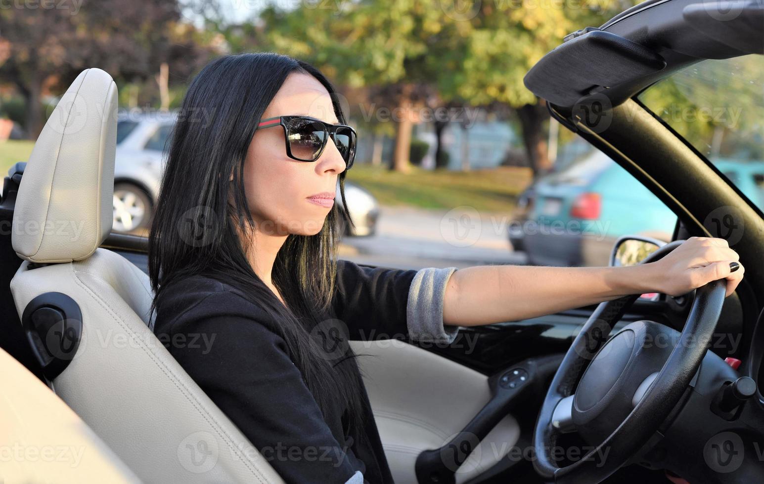 Happy beautiful woman driving a sports convertible car in the city photo