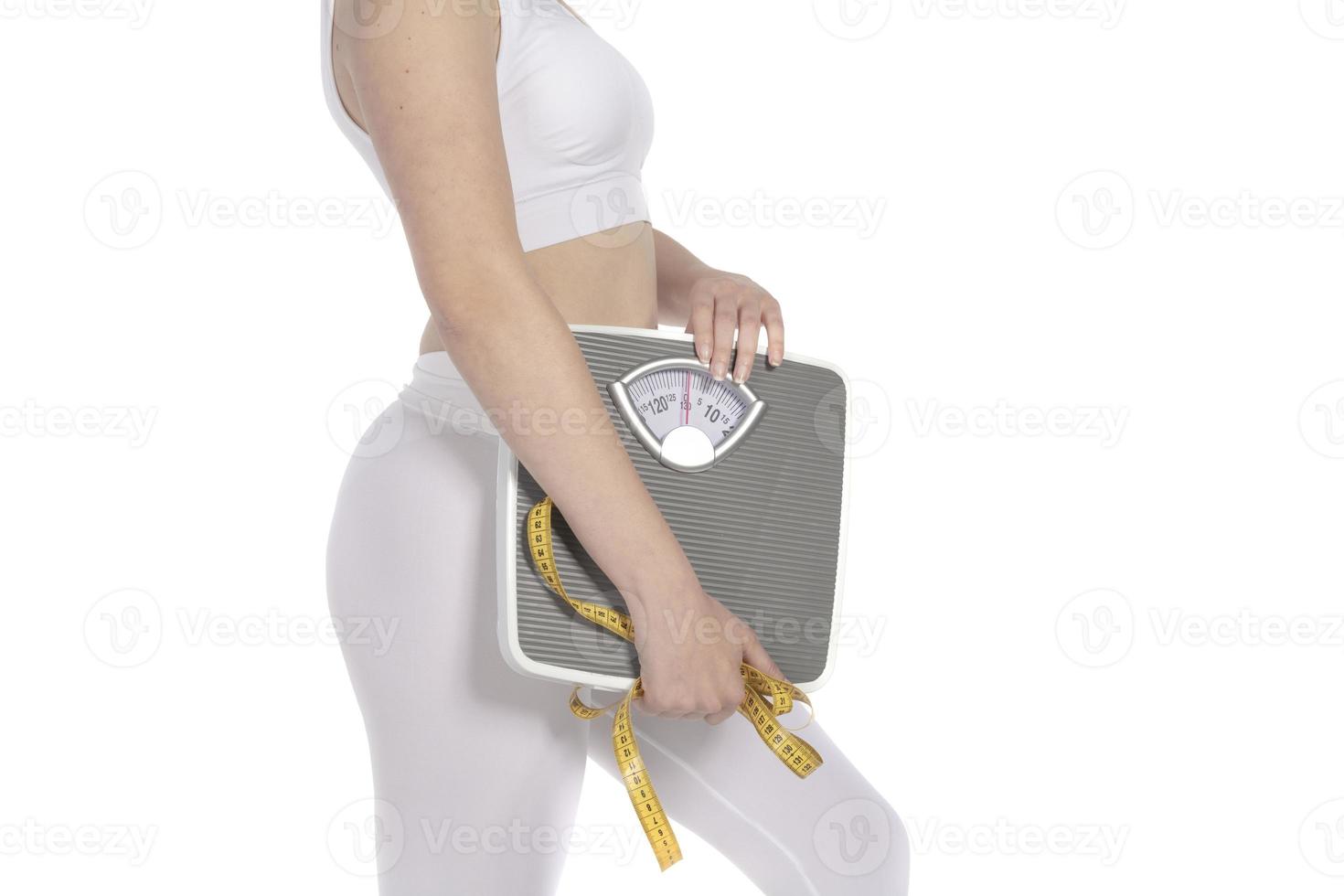 Female model holding scale and measuring tape over white background photo