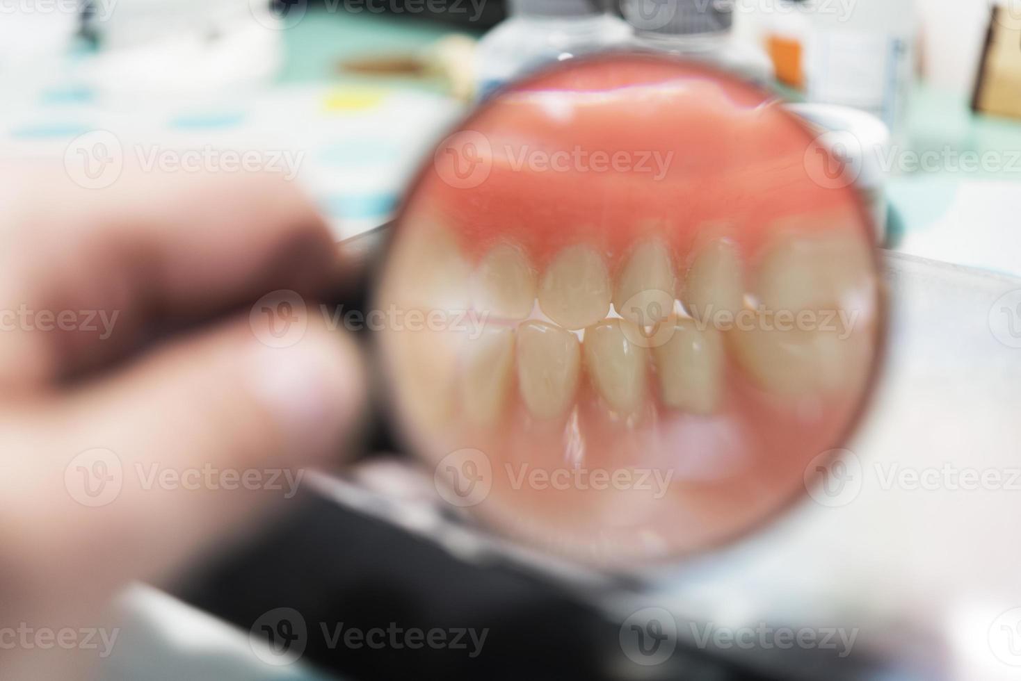 Dental prosthesis, dentures, prosthetics work. Prosthetics hands while working on the denture, false teeth, a study and a table with dental tools photo