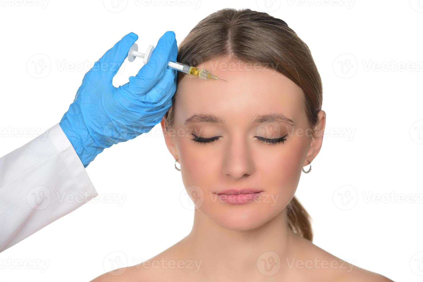 young woman gets injection of botox in her face. Woman in beauty salon. plastic surgery clinic. photo