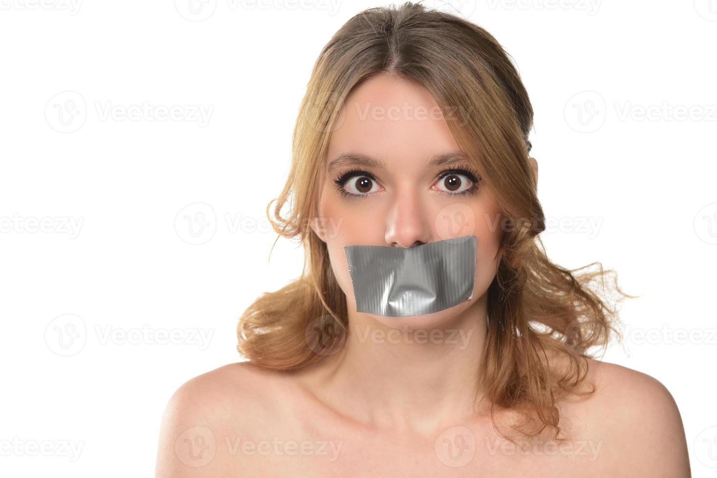 scared young woman with tape over her mouth. photo