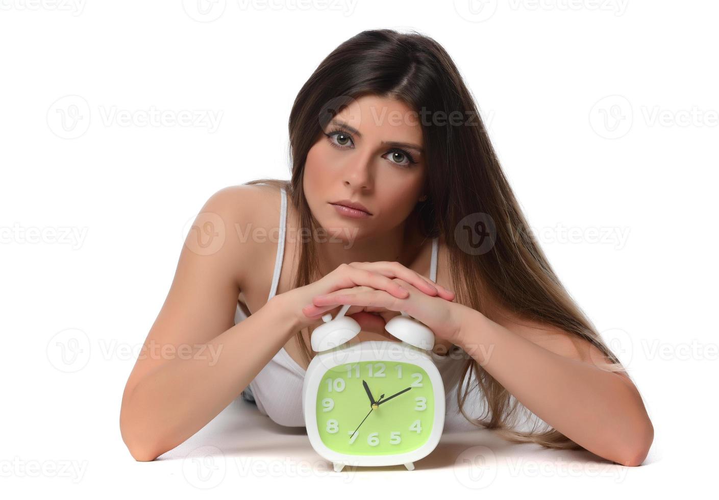 Beautiful sleeping woman resting in bed with alarm clock ready to wake her in the morning. photo