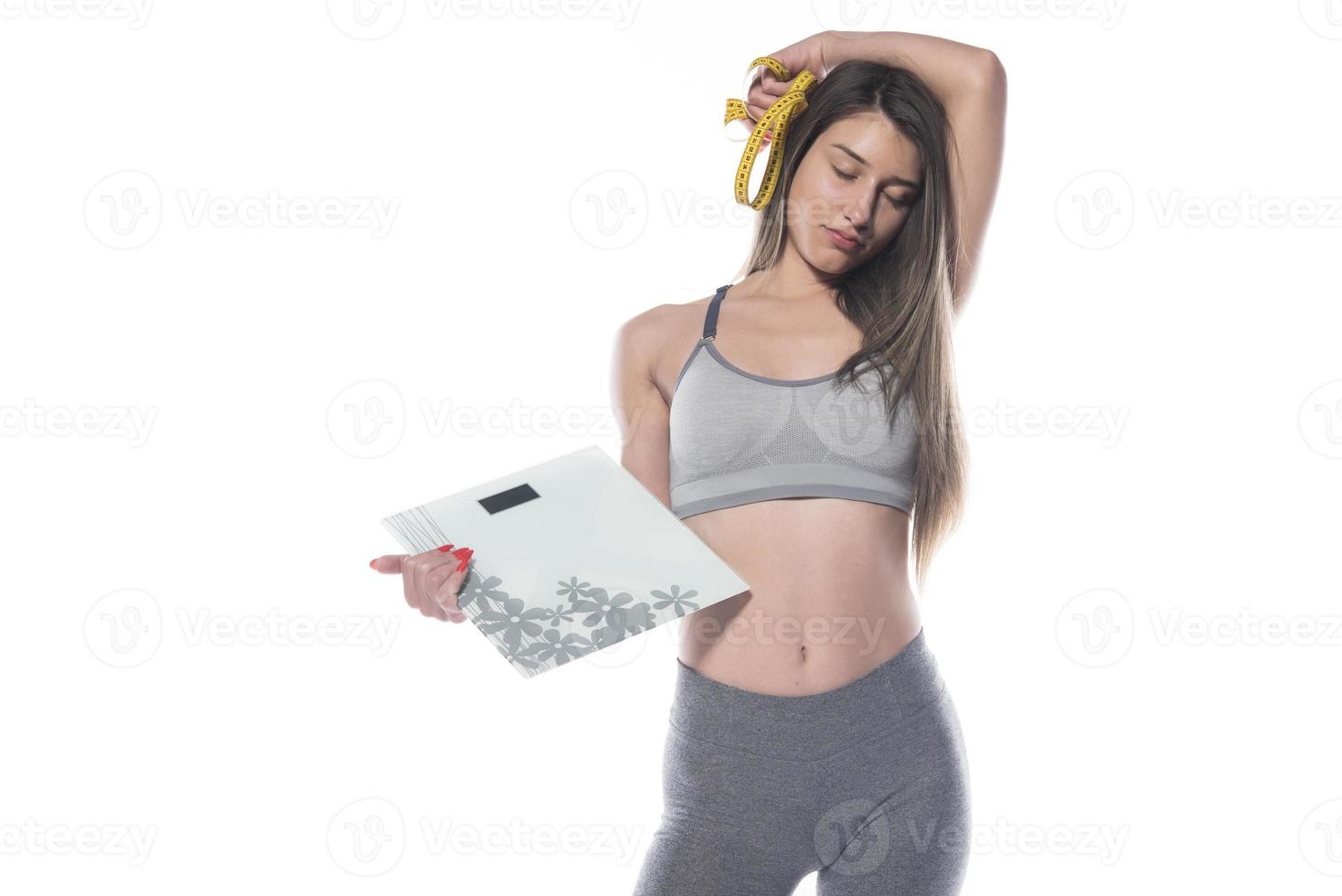modelo femenino sosteniendo escala y cinta métrica sobre fondo blanco foto
