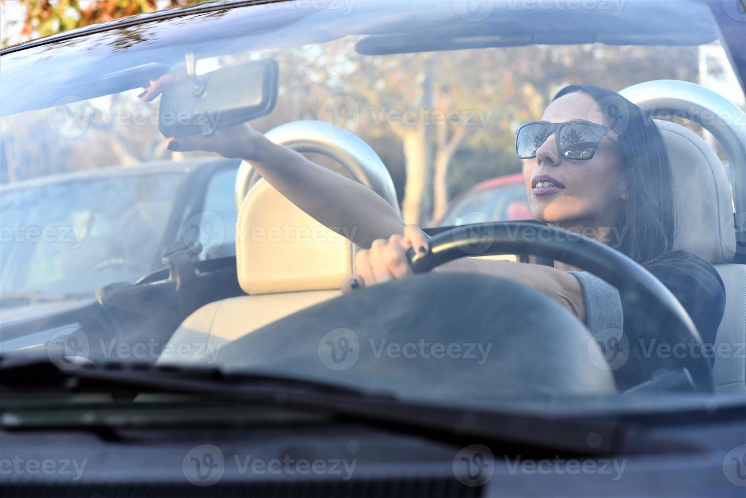 Happy beautiful woman driving a sports car in the city photo