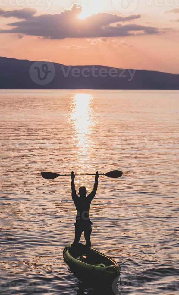 Handsome sporty man is kayaking on sunset photo