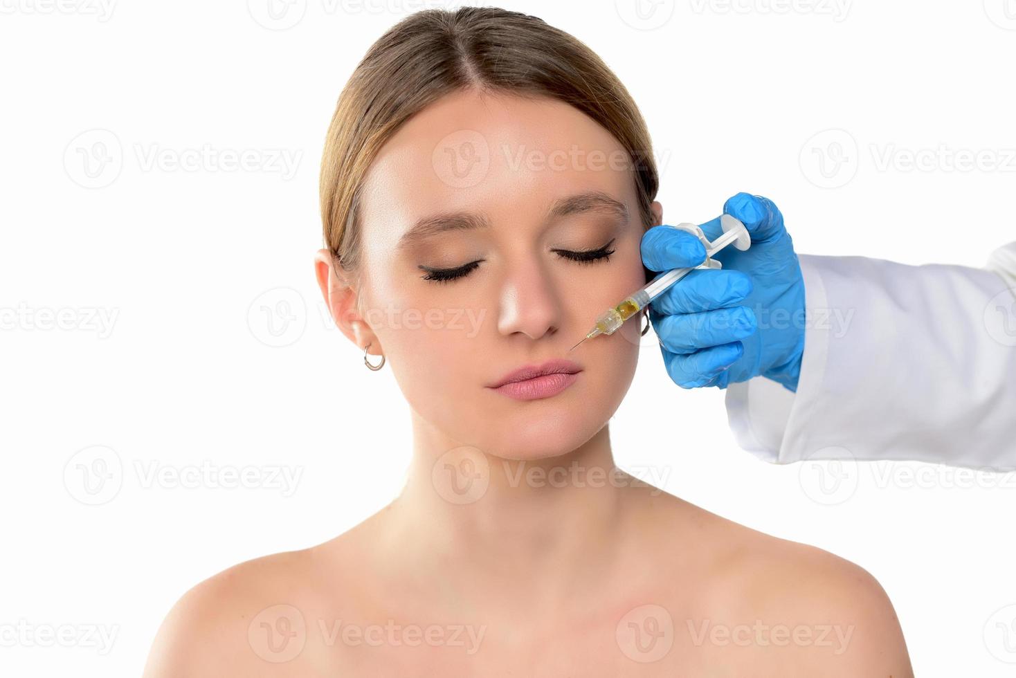 young woman gets injection of botox in her face. Woman in beauty salon. plastic surgery clinic. photo