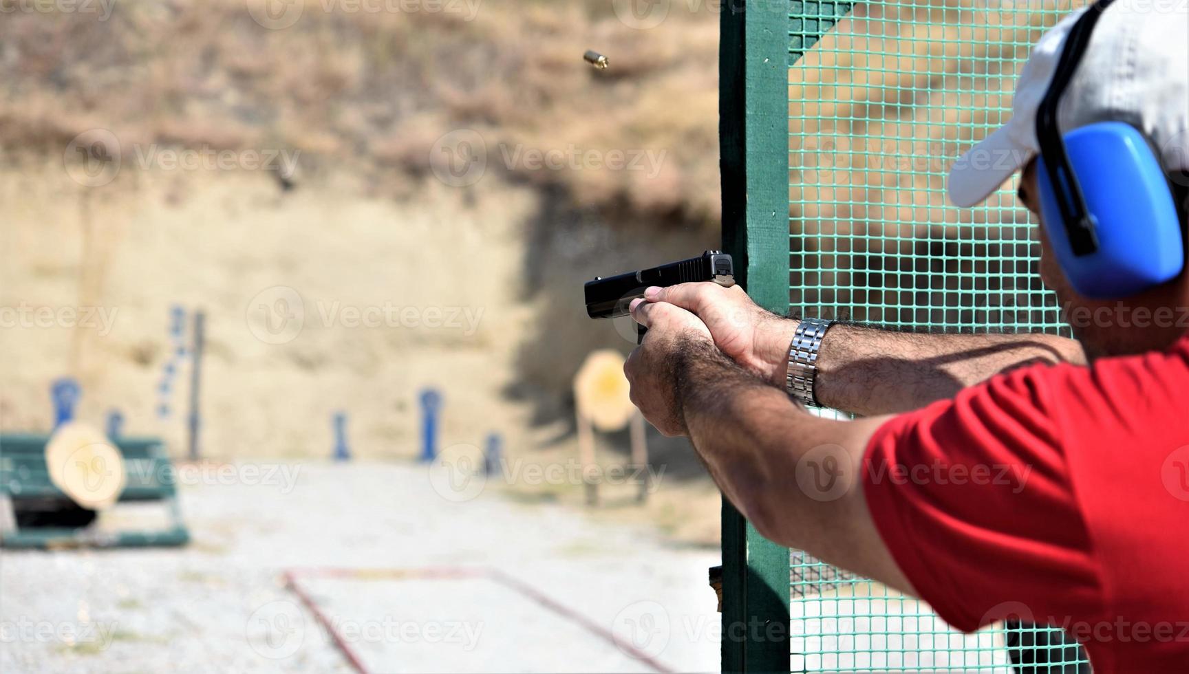 vista trasera de un hombre disparando su arma en un rancho de práctica. foto