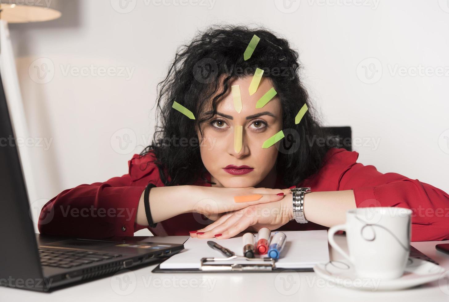 Pretty female model with a lot of post it notes working in her office. photo