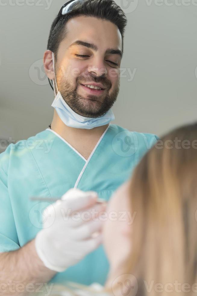 dentist curing patient's teeth filling cavity. Dentist working with professional equipment in clinic. photo