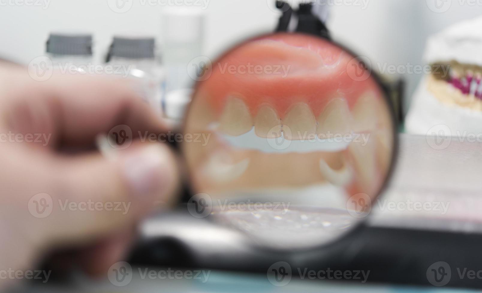 Dental prosthesis, dentures, prosthetics work. Prosthetics hands while working on the denture, false teeth, a study and a table with dental tools photo