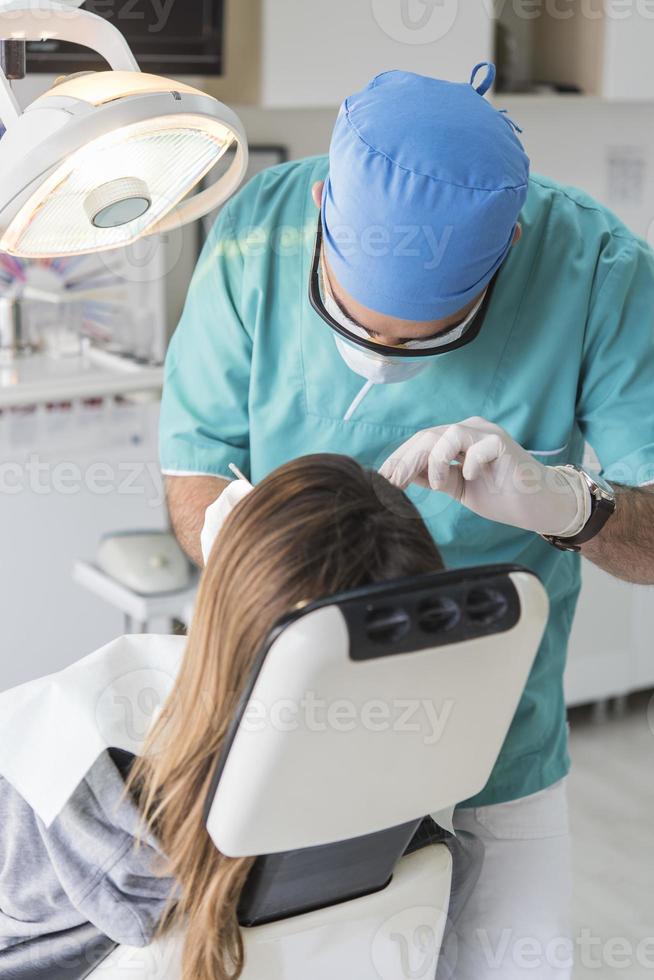 dentist curing patient's teeth filling cavity. Dentist working with professional equipment in clinic. photo