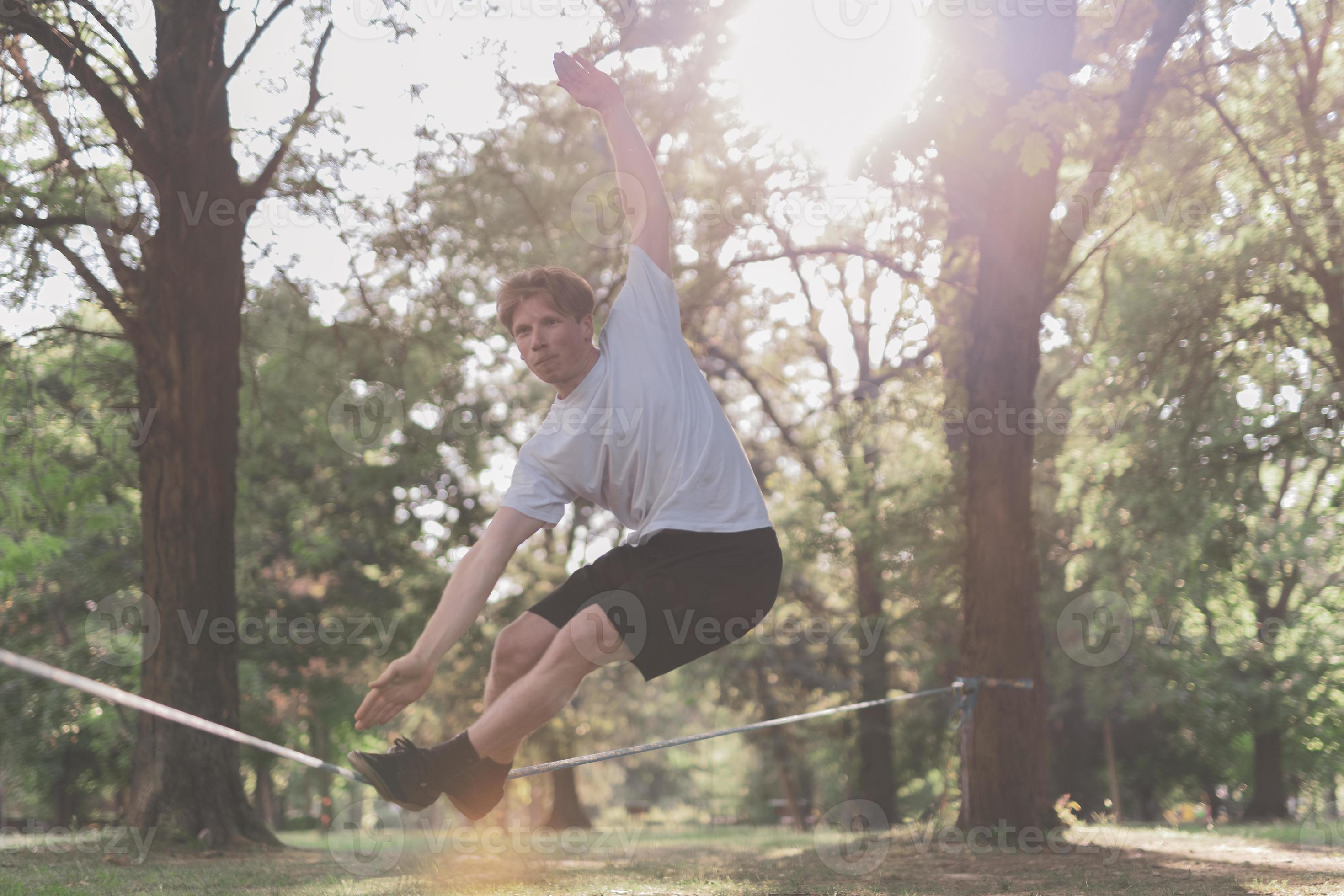 Young man balancing and jumping on slackline. Man walking, jumping and