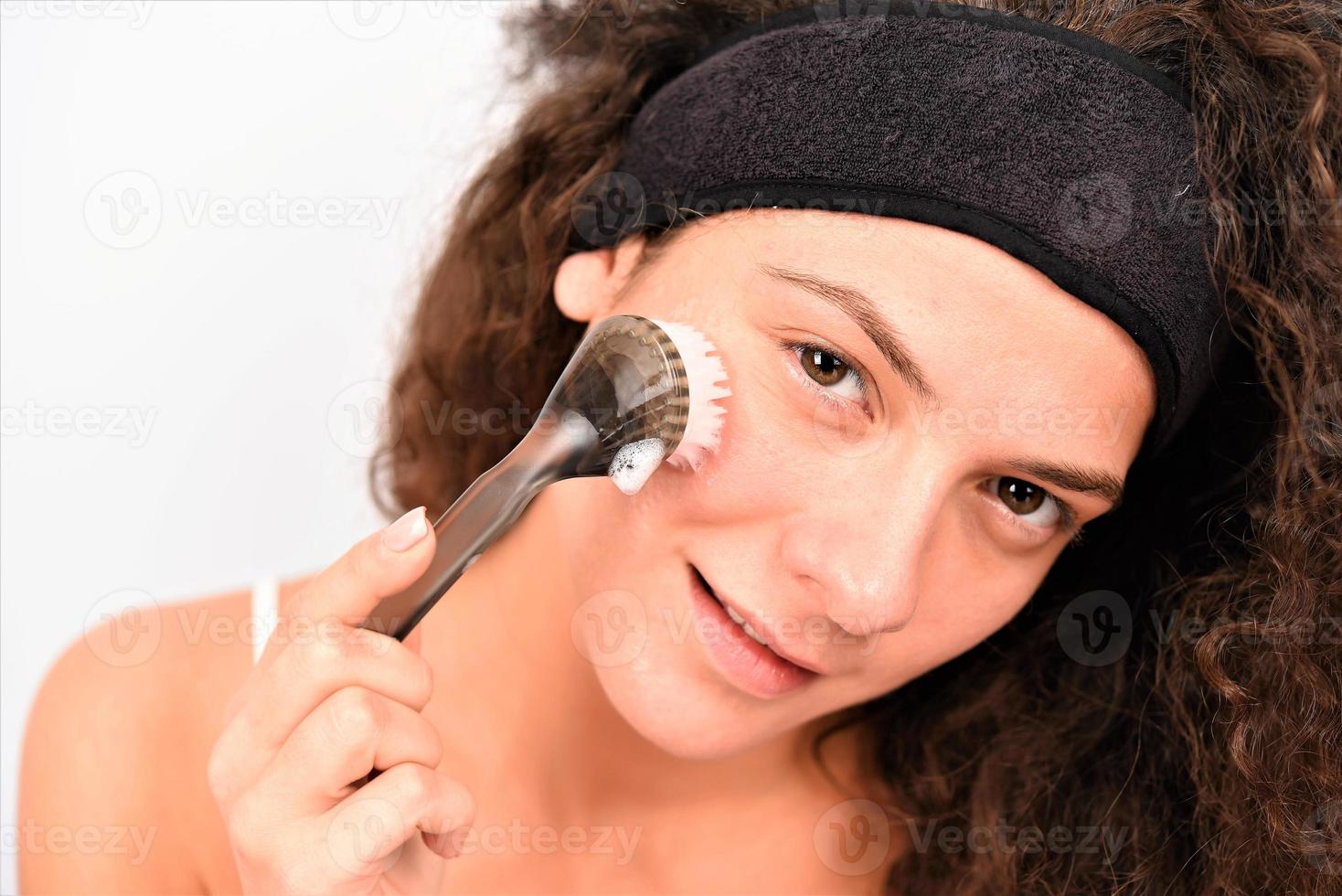 Beautiful young woman is washing her face with face brush 15985983