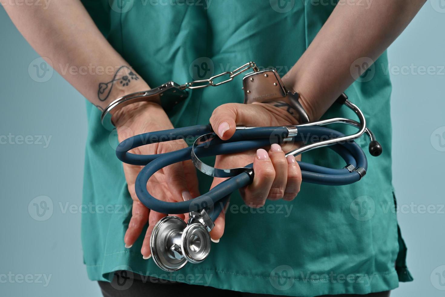 corrupted doctor holding stethoscope with handcuffs on his hands. corrupted health workers. photo