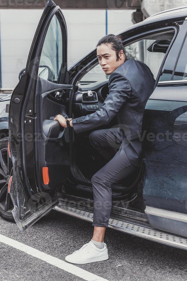 Asian business man getting out of his car on the parking lot photo