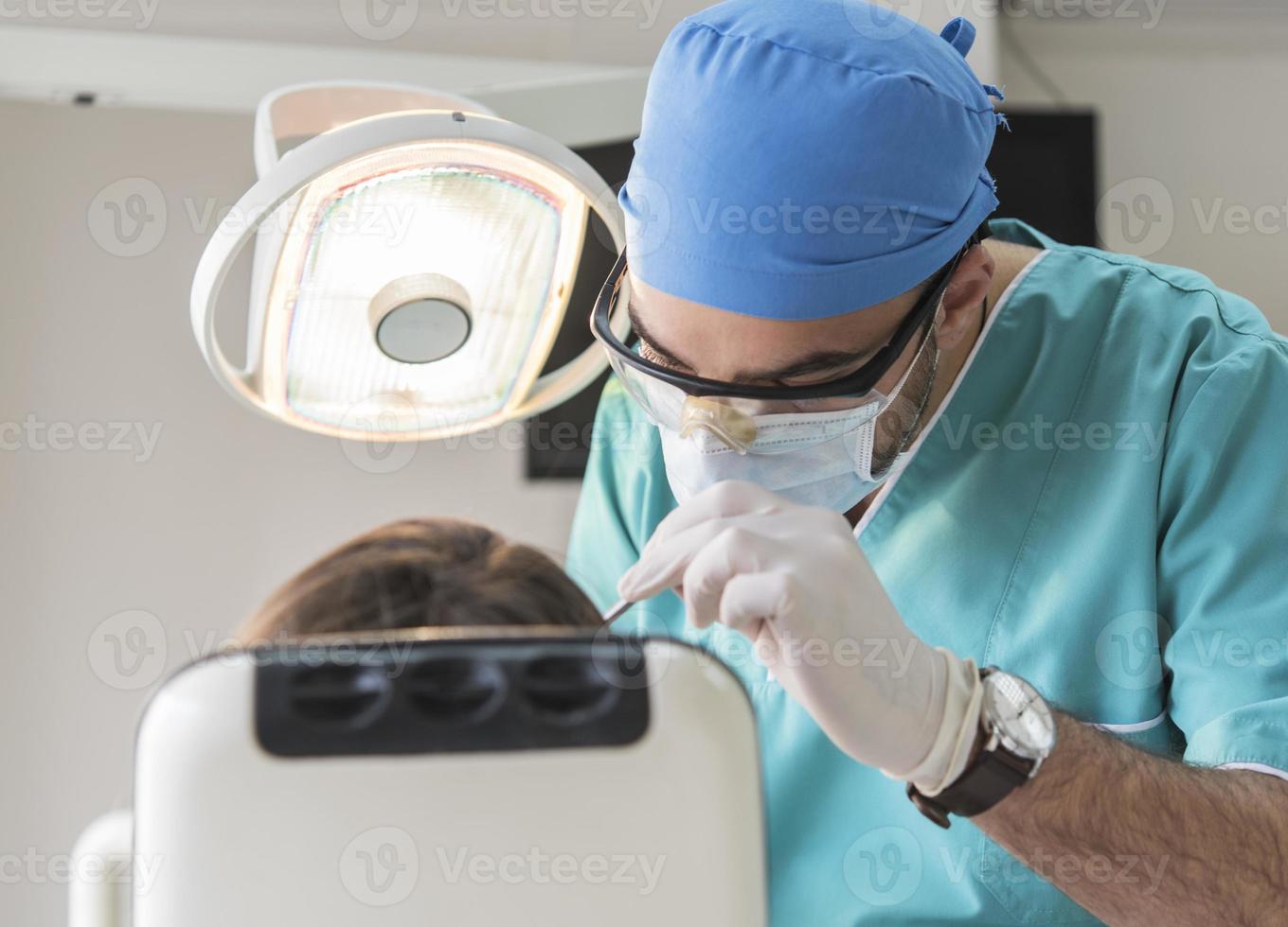 dentist curing patient's teeth filling cavity. Dentist working with professional equipment in clinic. photo