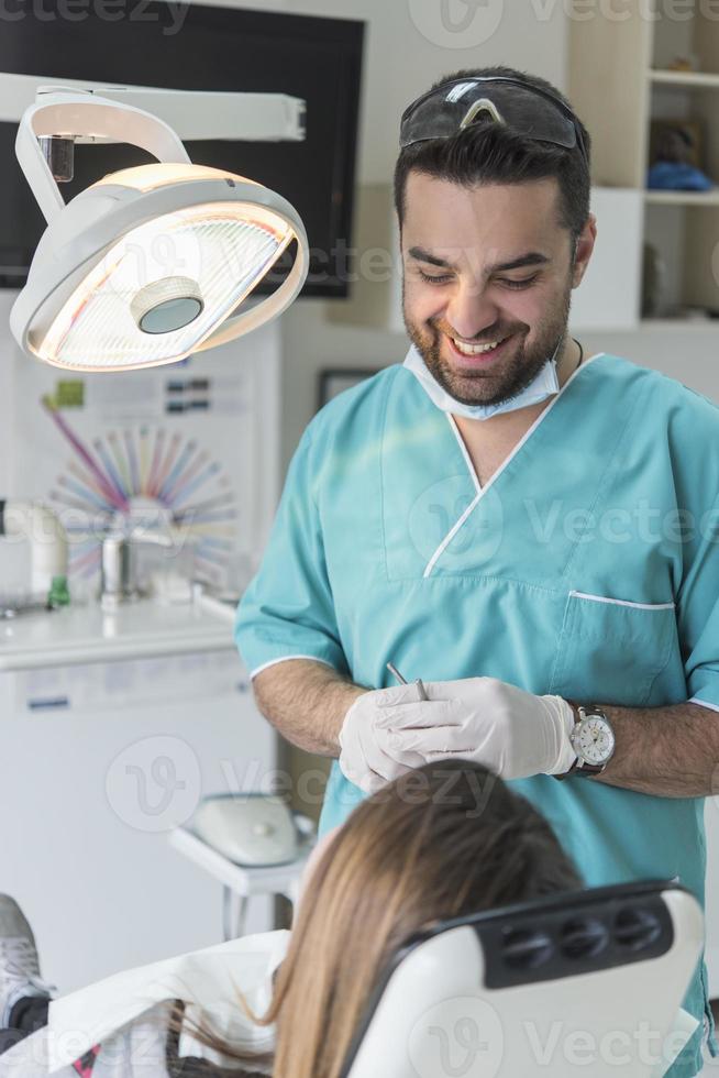 dentist curing patient's teeth filling cavity. Dentist working with professional equipment in clinic. photo