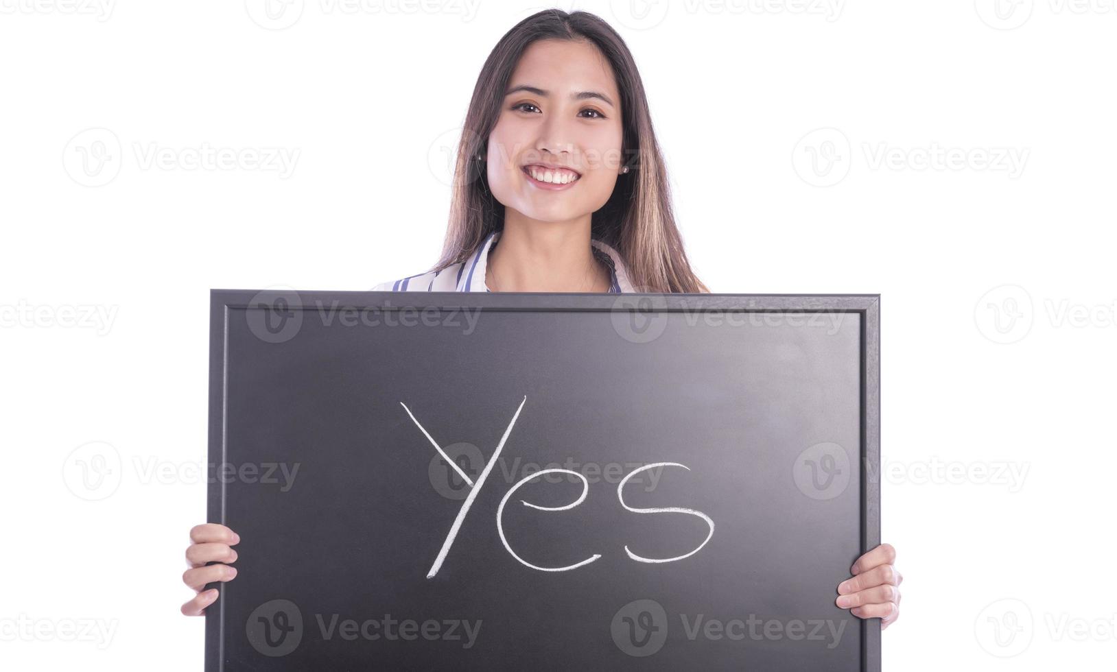Beautiful Asian female model pointing on wedding ring on her hand and holding blackboard with YES sign on it. photo