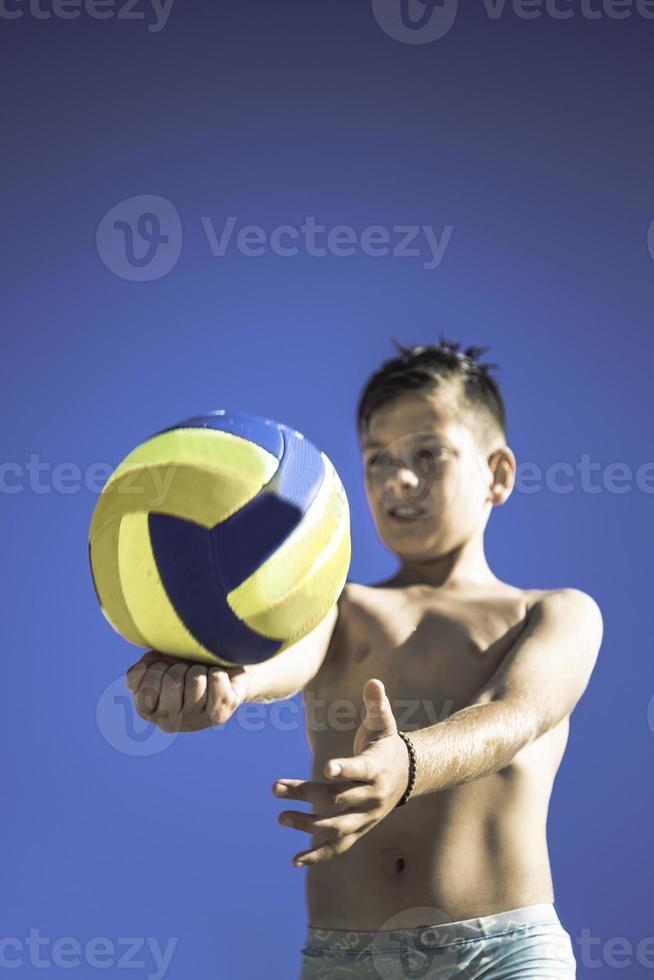 Kid plays volleyball on beautiful summer day photo