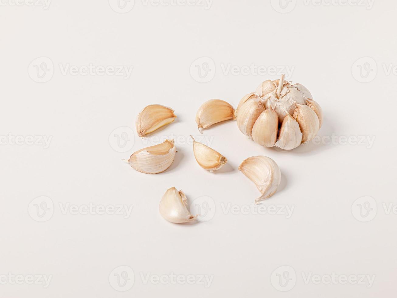 cabeza grande de ajo y dientes pequeños dispuestos sobre fondo blanco apártese para tener espacio para copiar. foto