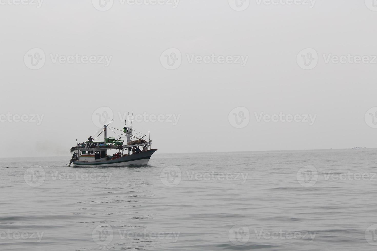 Small fishing boat sailing in an open Indonesian sea against clear sky. photo