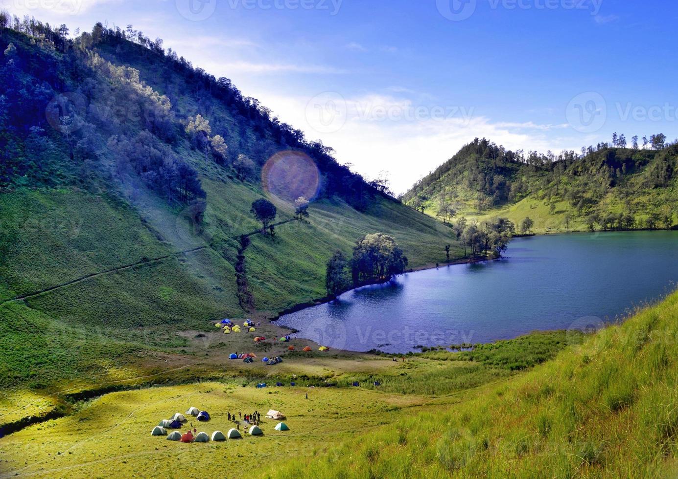 High Angle Scenic View Of Ranu Kumbolo Lake Against Blue Sky with lots of tents in the field. Located in Ranu Kumbolo Semeru, Indonesia photo