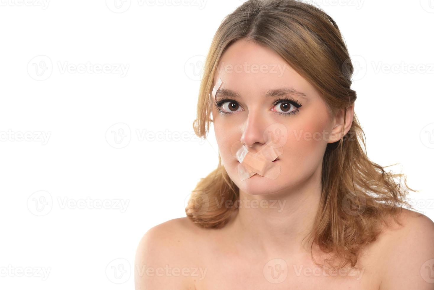 scared young woman with tape over her mouth. photo