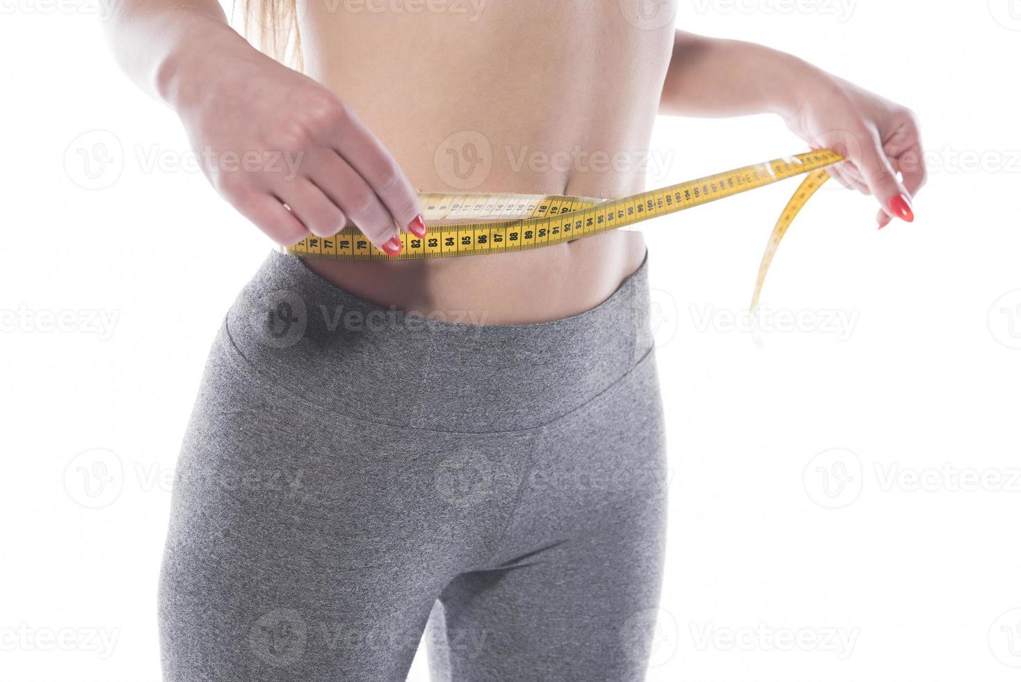 Young woman measure her waist with measure tape photo