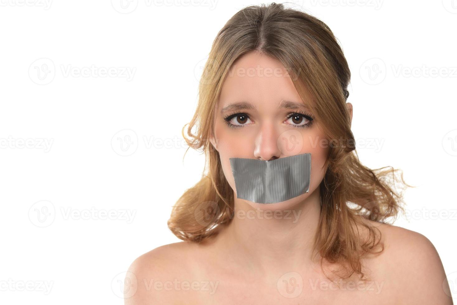 scared young woman with tape over her mouth. photo