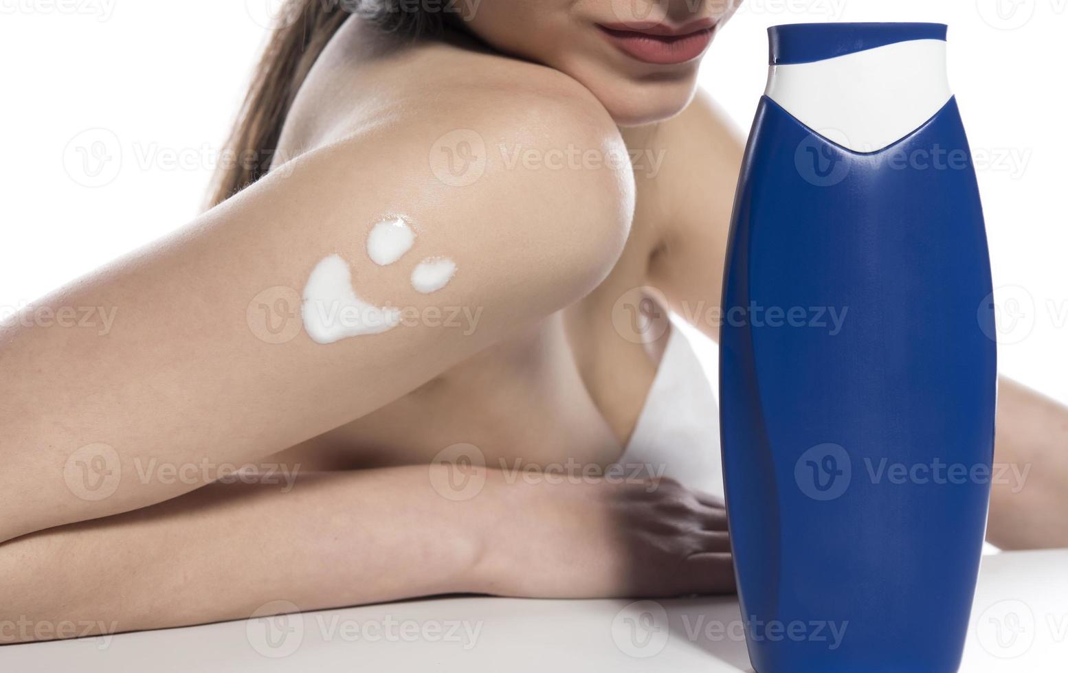 hermosa mujer de piel aplicando loción corporal sobre fondo blanco foto