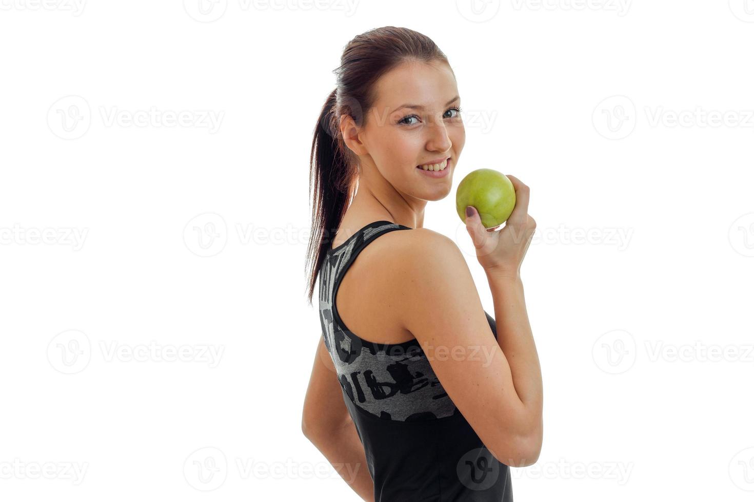 joyful young gymnast stands sideways and holding a Green Apple close-up photo