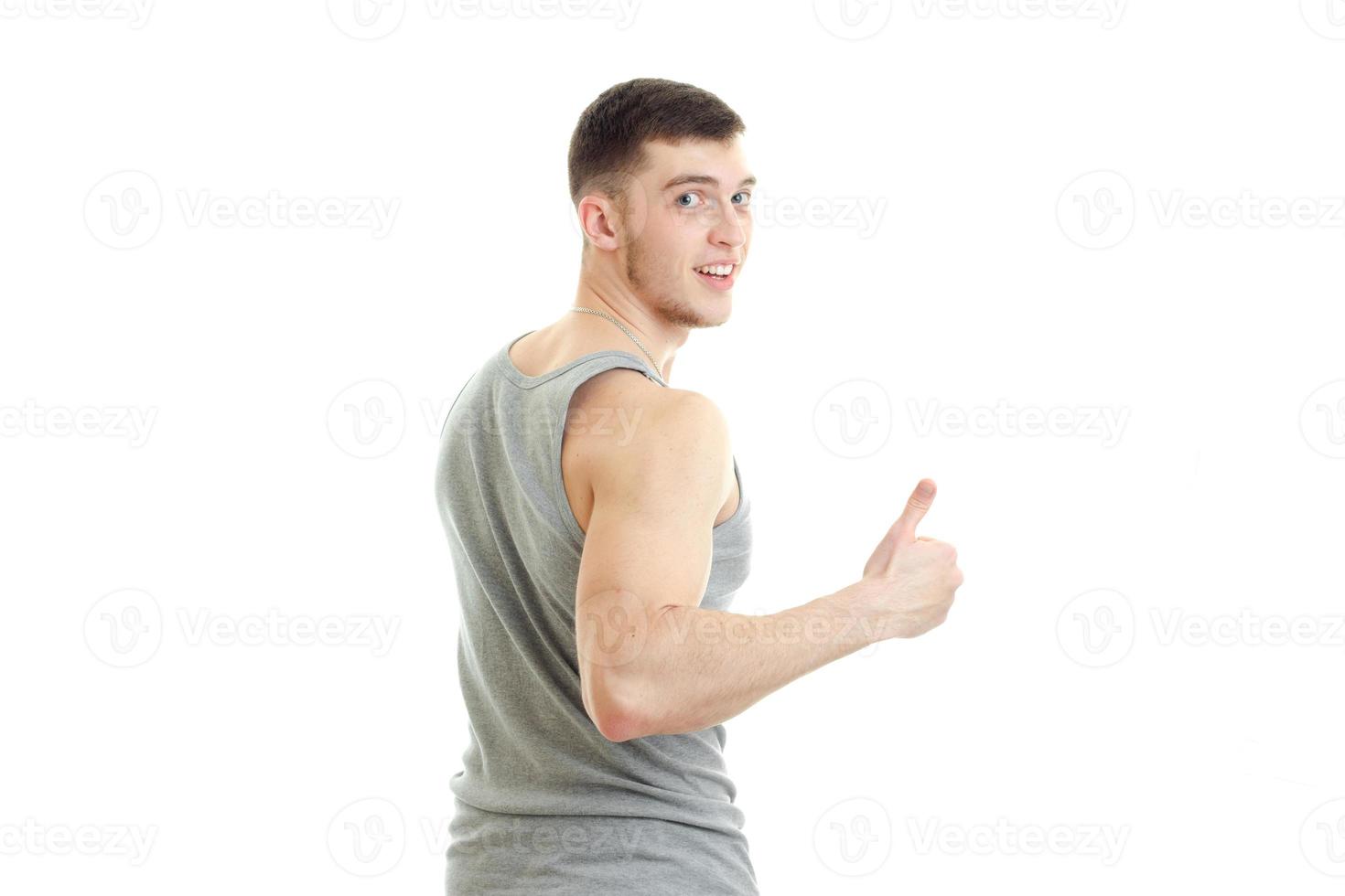 sporty young man with muscles turned his back to the camera smiling and shows the class photo