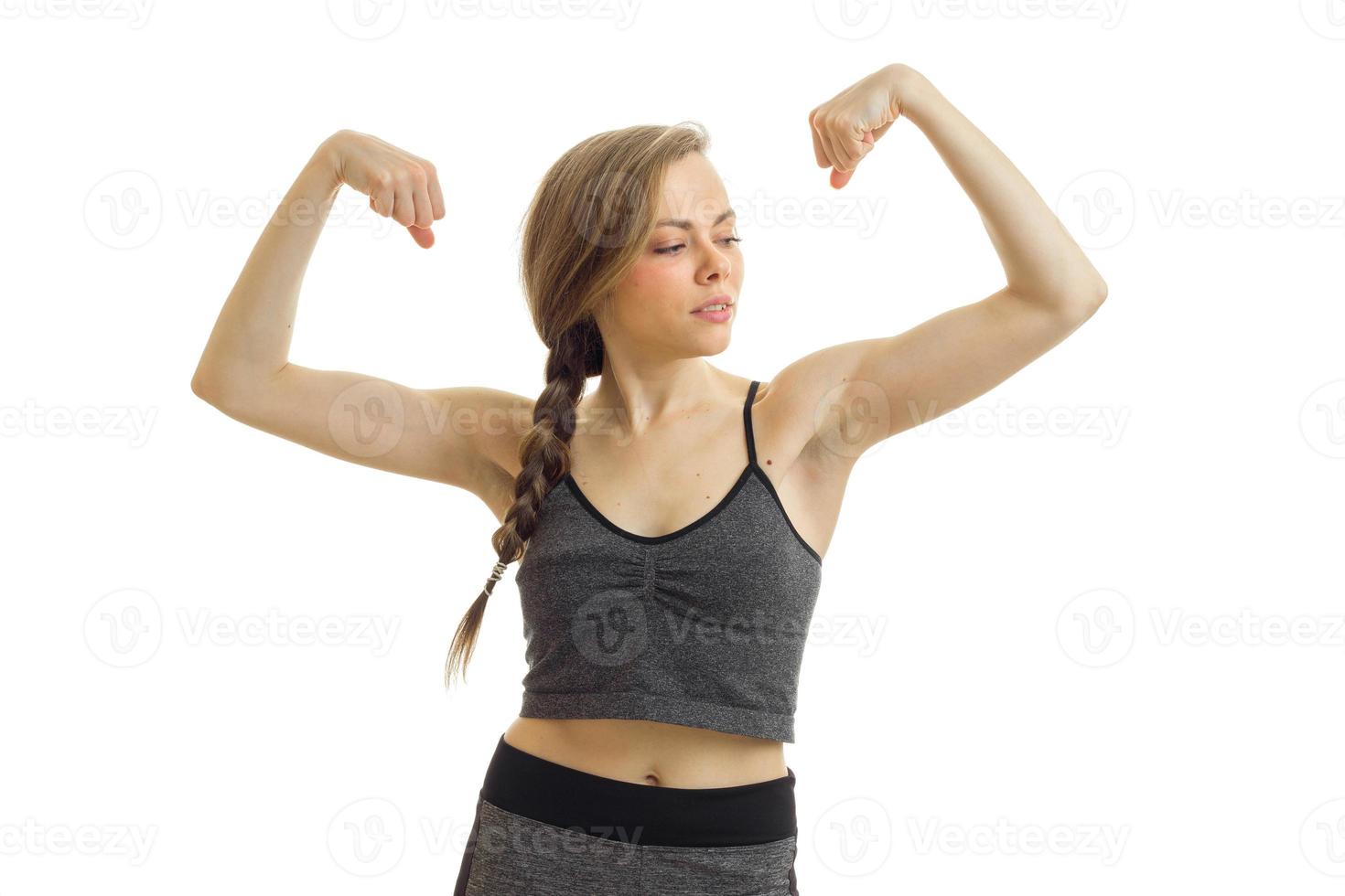 beautiful fitness girl grey top looks to the side and shows off her biceps at the hands of a close-up photo