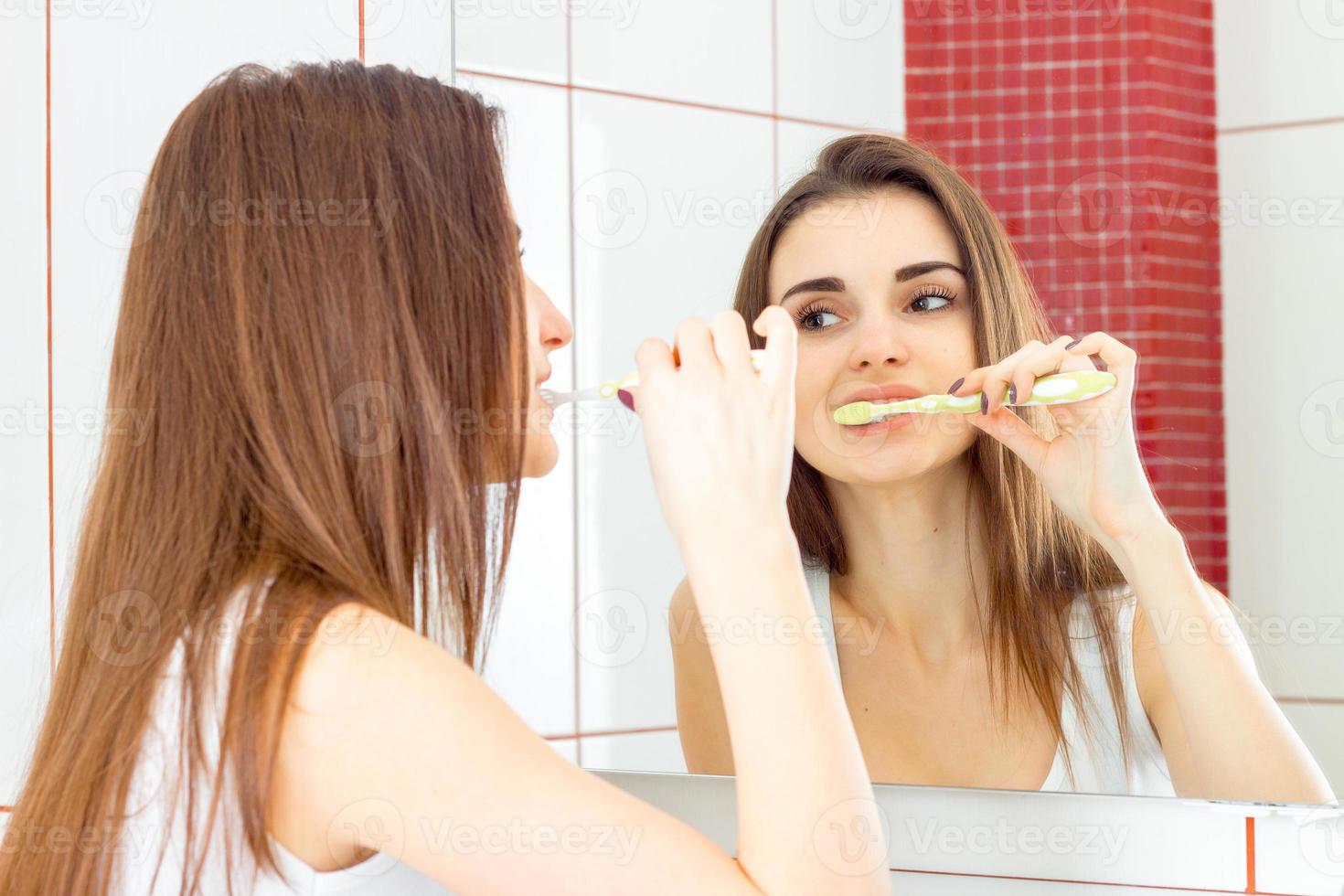 una mujer joven cepillándose los dientes foto