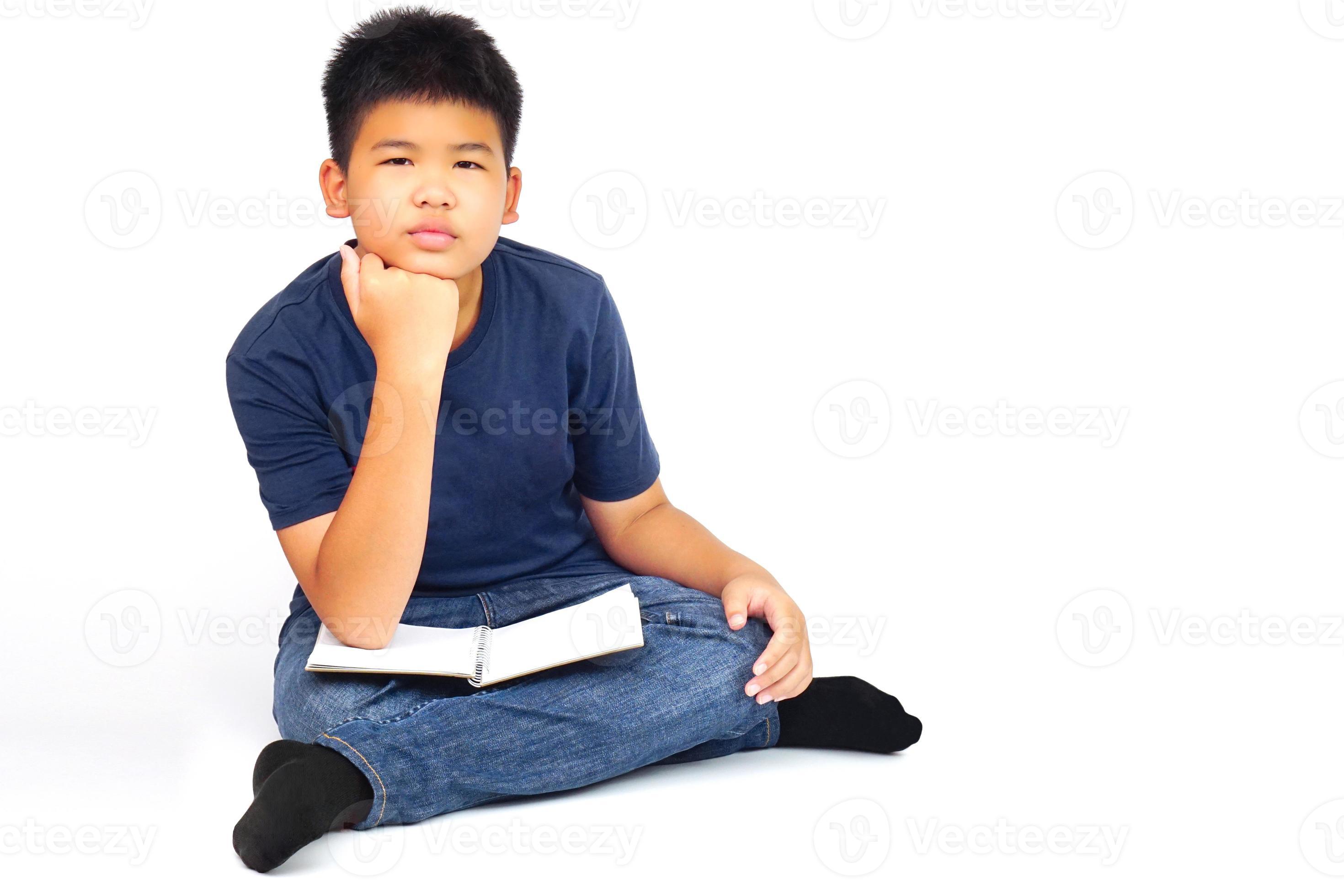 Young asian boy sitting crosslegged, with resting his chin on his hand
