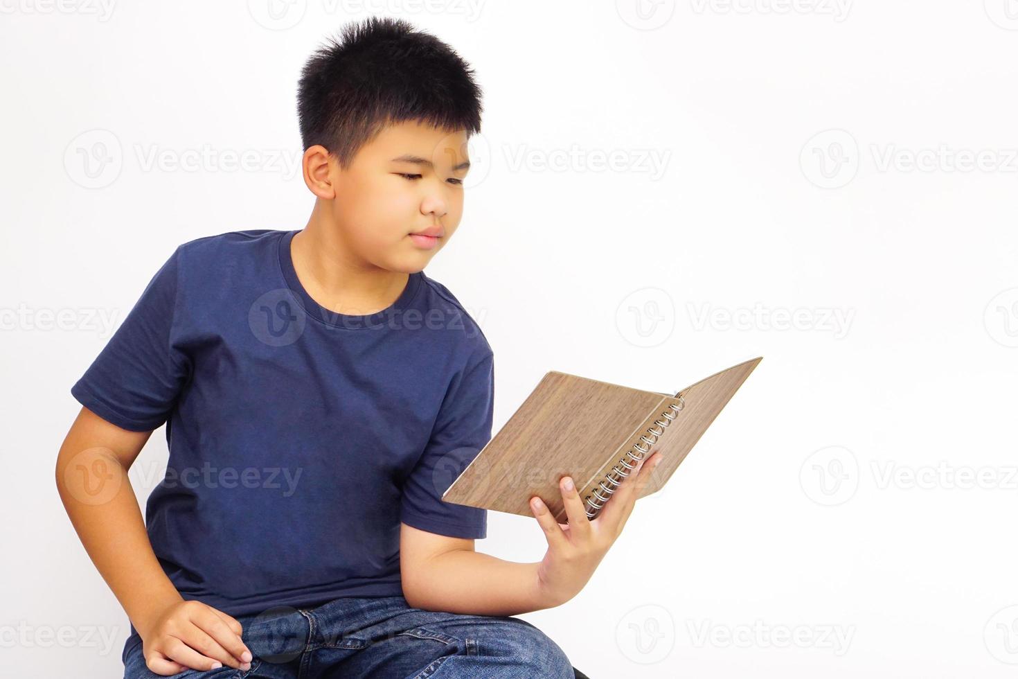 Young boy sitting happily read a book. Education and learning concept. photo